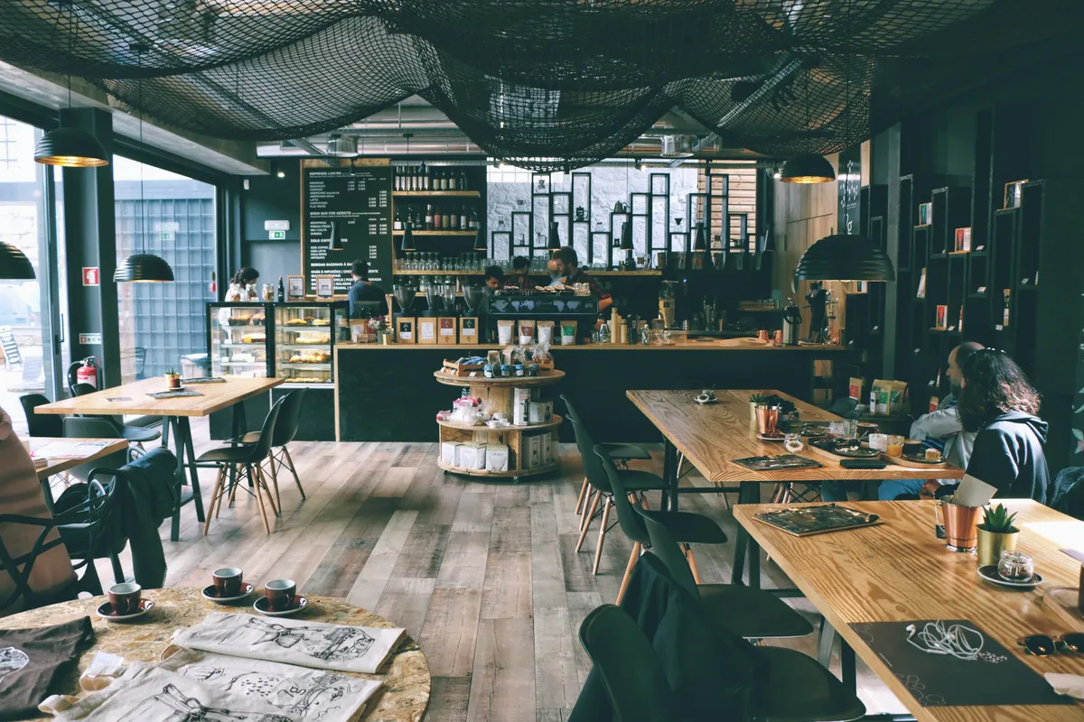 A café interior with wooden tables, hanging lights and a counter